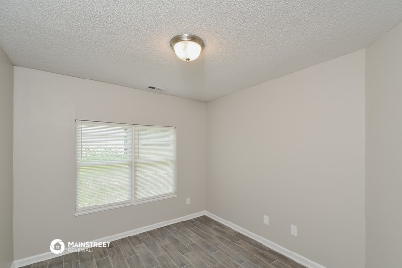 the spacious living room with a large window and wood flooring