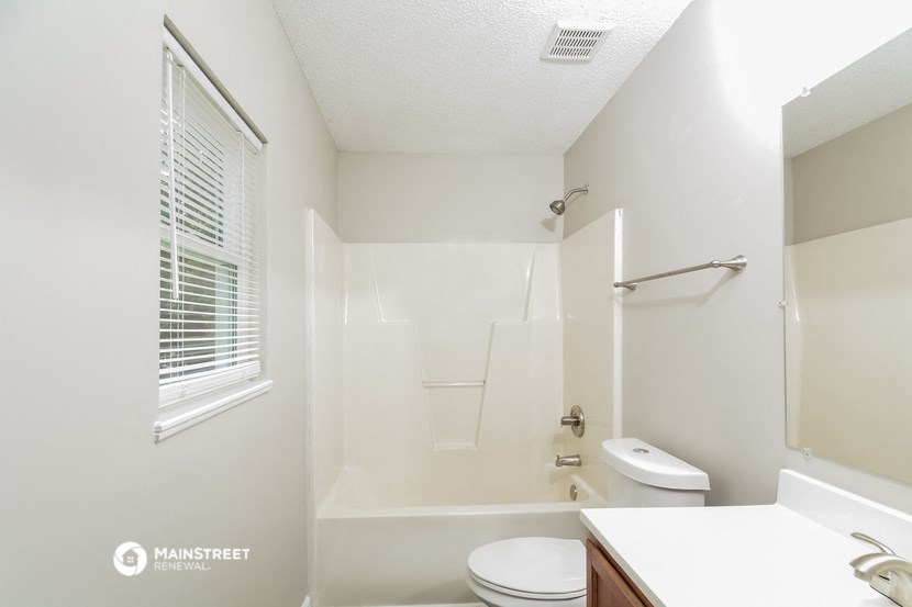a bathroom with a shower toilet and sink and a window