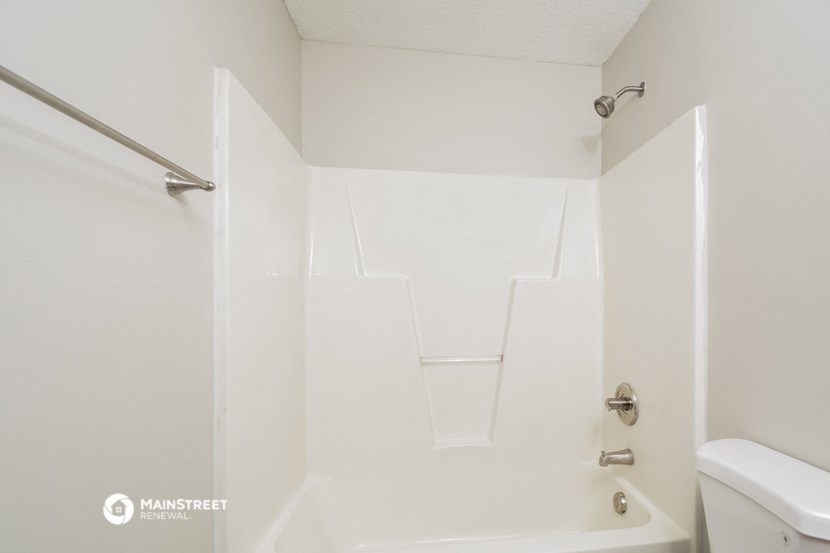 a bathroom with white walls and a white tub and a toilet