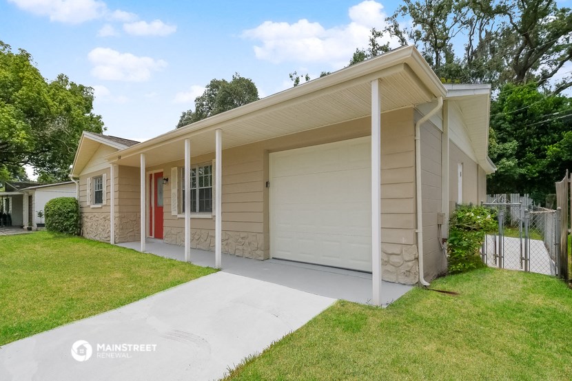 a small tan house with a driveway and a white garage door