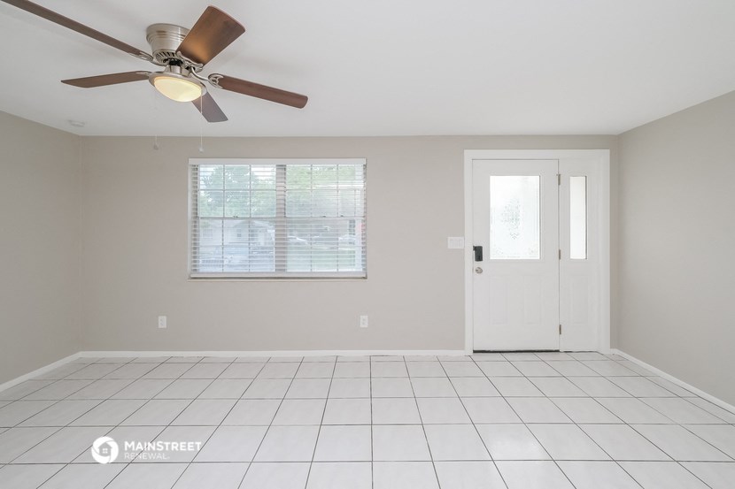 an empty living room with a ceiling fan and a door