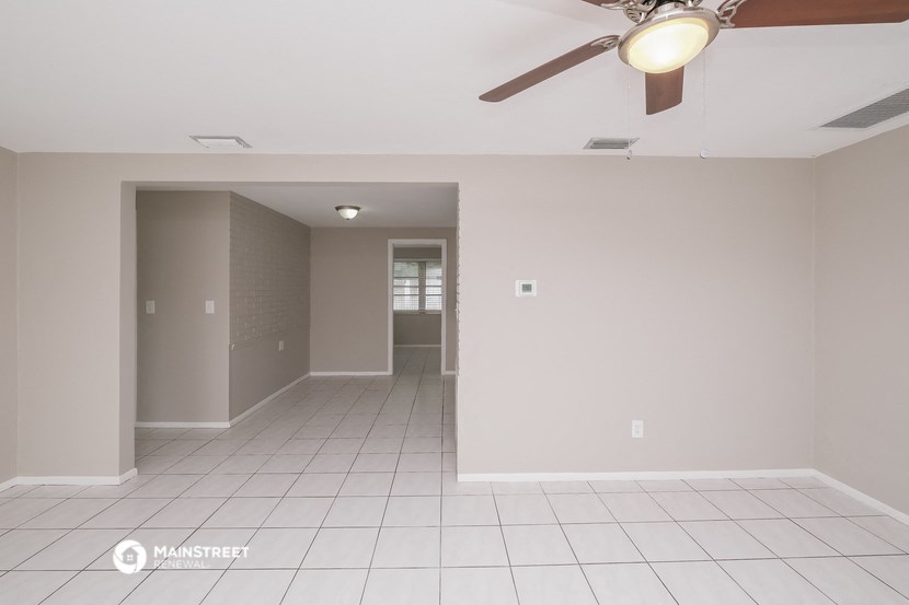 an empty living room with a ceiling fan