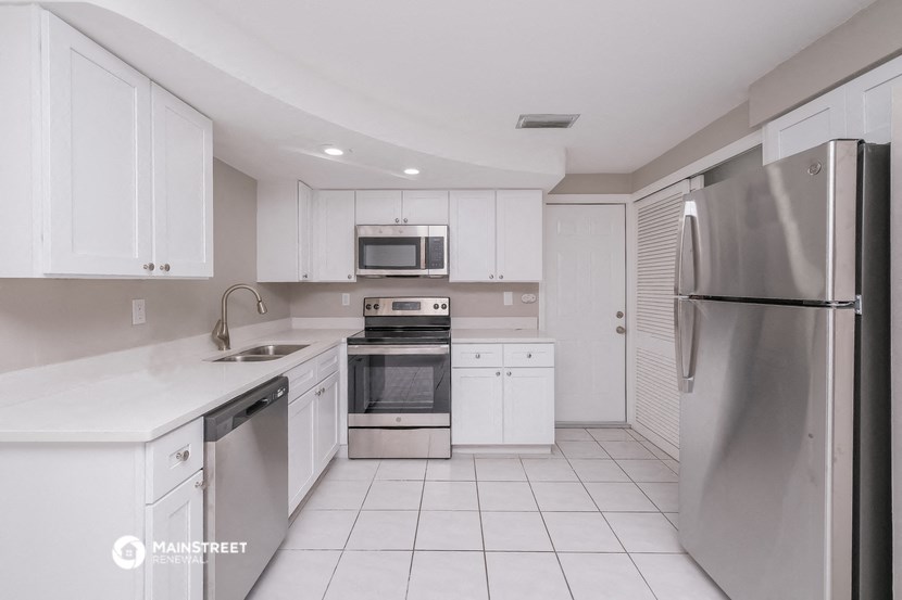 a white kitchen with stainless steel appliances and white cabinets