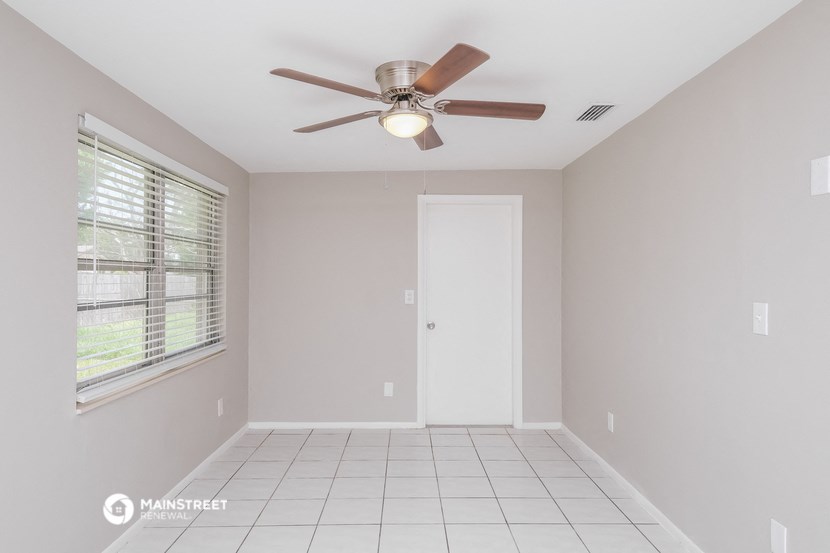 an empty room with a ceiling fan and a window