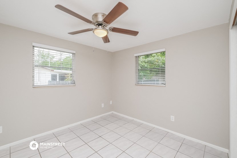 the bedroom has a ceiling fan and a tiled floor