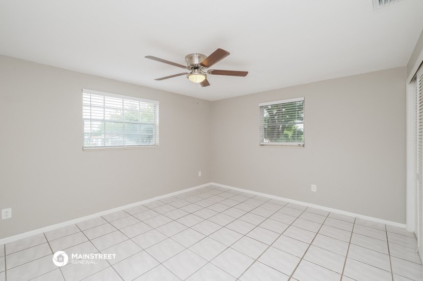an empty living room with a ceiling fan and a tiled floor