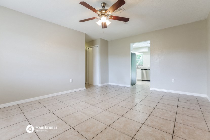 the spacious living room with tile flooring and a ceiling fan