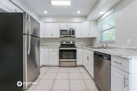 the kitchen has stainless steel appliances and white cabinets