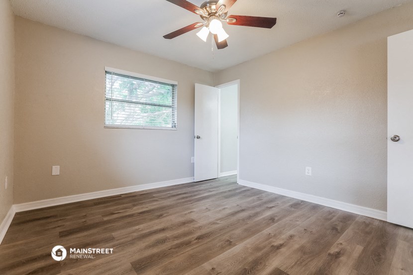the spacious living room with hardwood floors and a ceiling fan