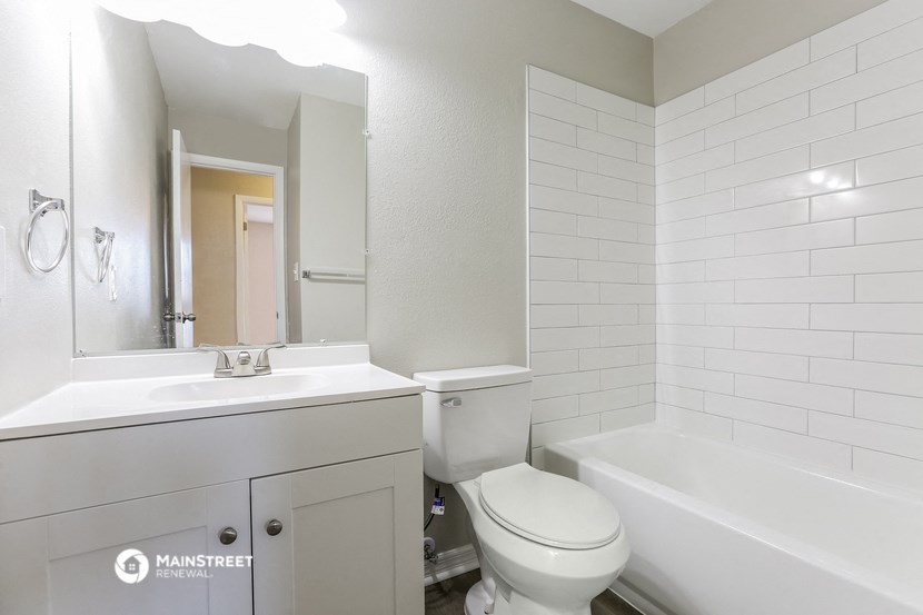a bathroom with a toilet sink and tub and a mirror