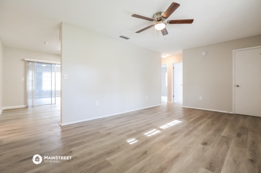 an empty living room with white walls and a ceiling fan