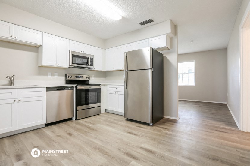 an empty kitchen with stainless steel appliances and white cabinets