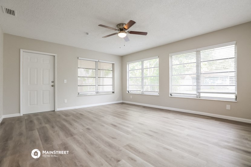 the spacious living room with wood flooring and a ceiling fan