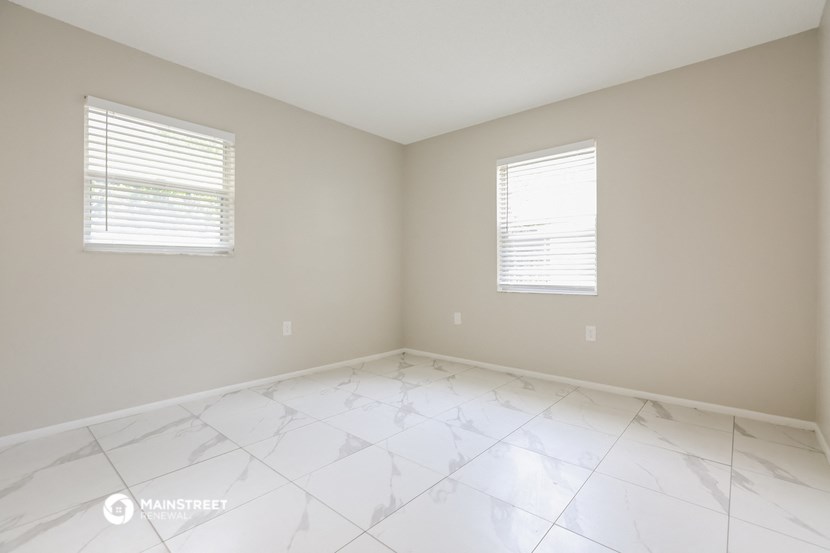 an empty room with two windows and white marble flooring