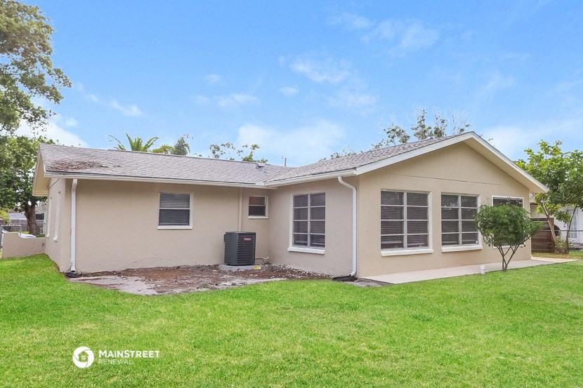 a small tan house with a yard and a green lawn