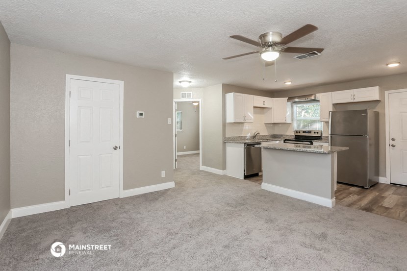 a living room with a kitchen and a ceiling fan