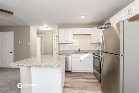 a white kitchen with stainless steel appliances and granite counter tops