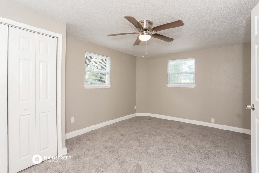 an empty bedroom with a ceiling fan and a closet
