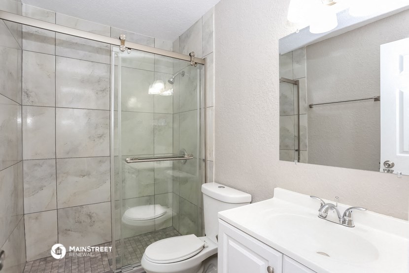 a bathroom with a glass shower and a sink and a toilet