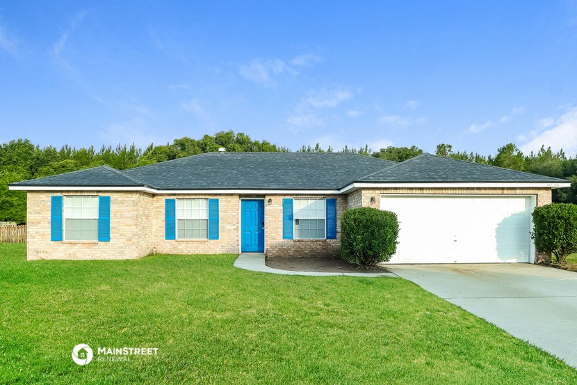 a tan brick house with blue shutters and a blue garage door