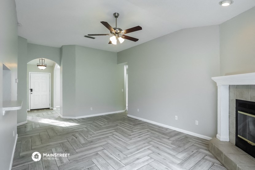 the living room with a fireplace and a ceiling fan