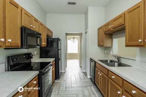 a kitchen with wood cabinets and black appliances and white counter tops