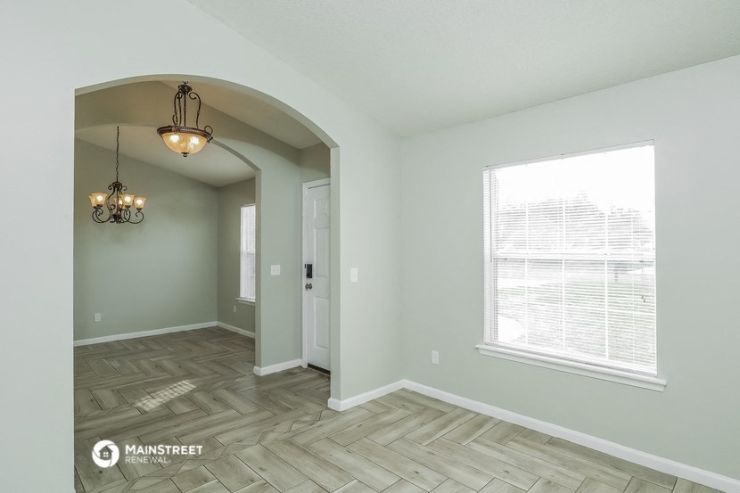 the spacious living room with a large window and wood flooring