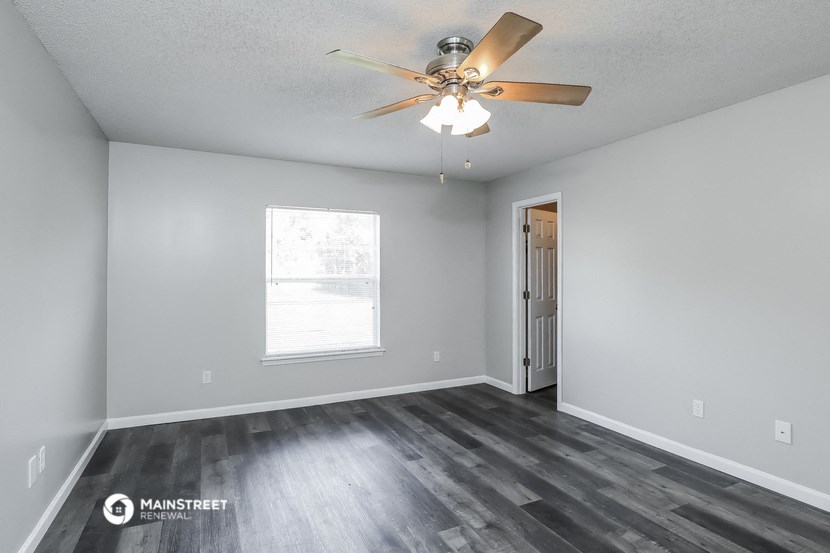 the spacious living room with wood flooring and a ceiling fan