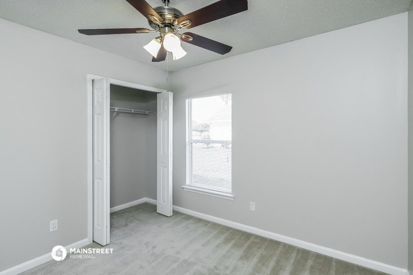 an empty bedroom with a ceiling fan and a closet
