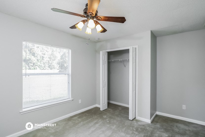 a bedroom with a ceiling fan and a closet