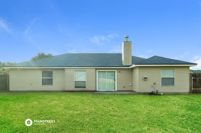 a tan house with a green lawn and a blue sky