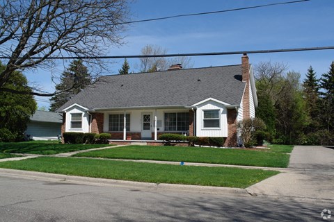 a house on the corner of a street with grass