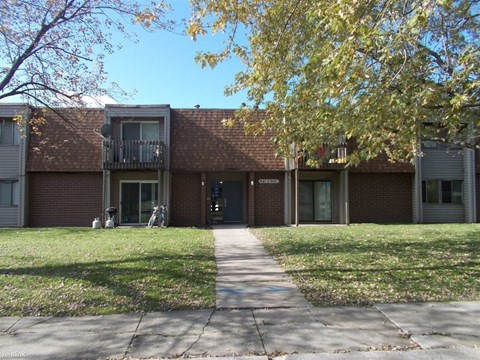 the front of a brick building with a sidewalk and grass