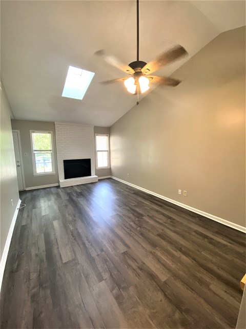 an empty living room with wood floors and a ceiling fan
