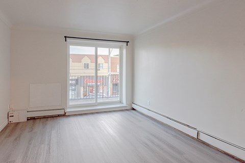 an empty living room with a large window and wood floors