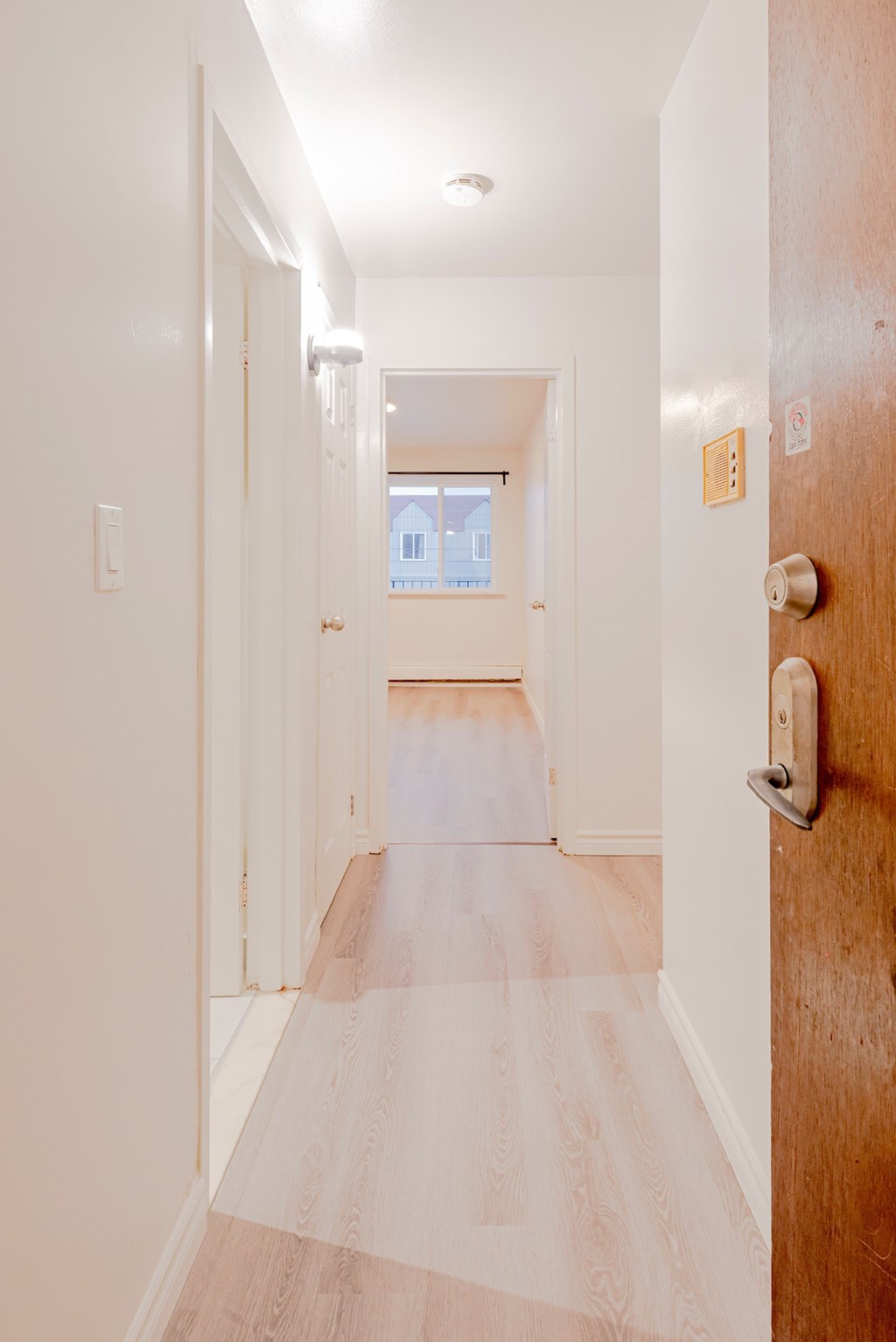 a hallway with wood floors and white walls and a door with a handle