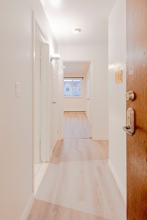 a hallway with wood floors and white walls and a door with a handle