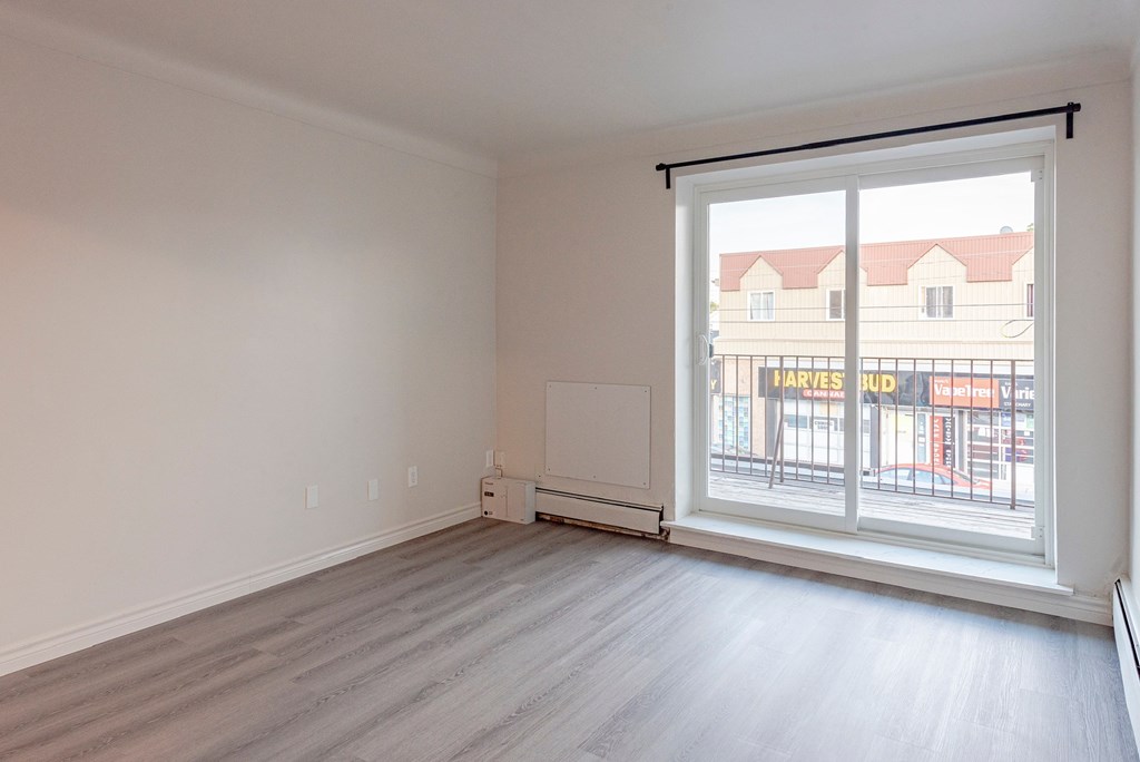 an empty living room with a large window and wooden floors