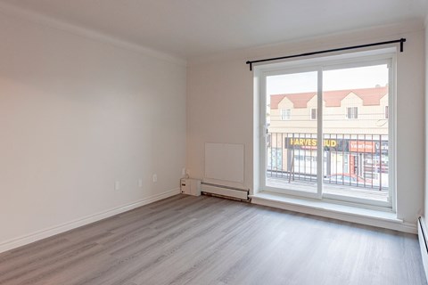 an empty living room with a large window and wooden floors