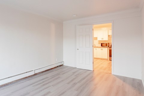 a living room with white walls and a door to a kitchen