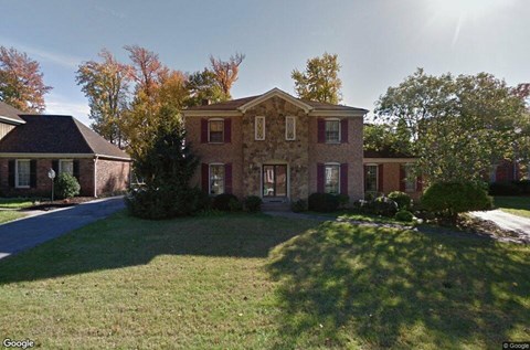 a brick house with a lawn and a driveway