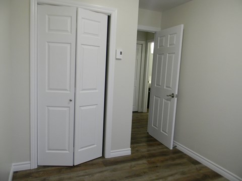 a bedroom with two doors and a hallway with a door open to a closet