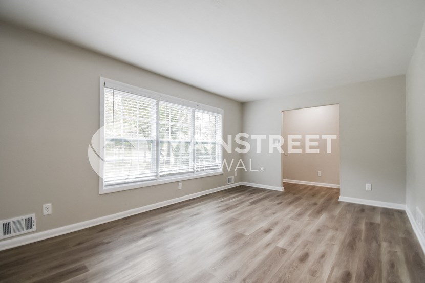 an empty living room with a large window and wood floors