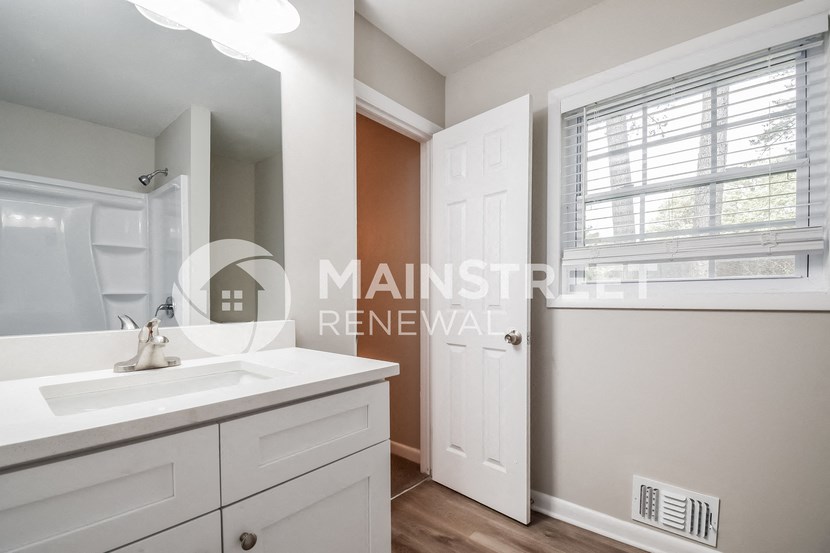 a white bathroom with a sink and a white door