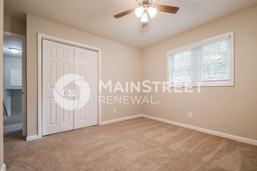 a bedroom with a white door and a ceiling fan