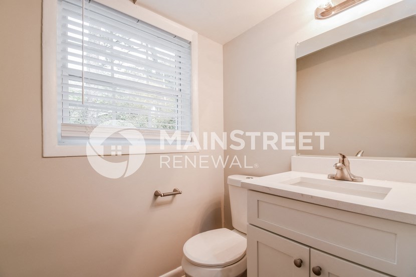 a bathroom with a toilet and a sink and a window