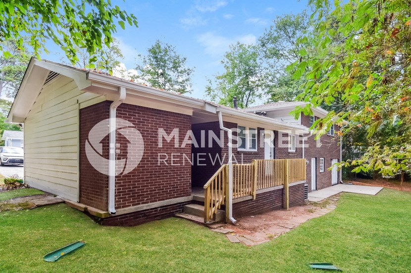 a small brick house with a porch and a lawn