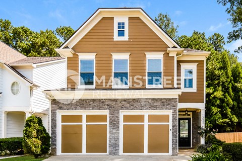 a two story house with brown siding and white garage doors