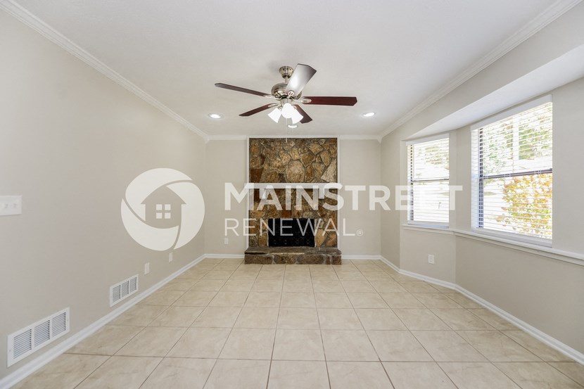 a renovated living room with a fireplace and a ceiling fan