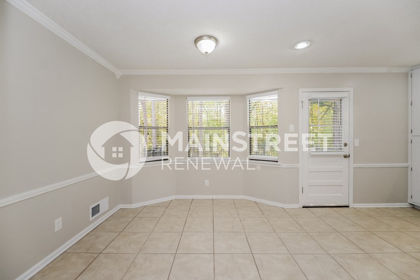 a large empty living room with a white door and windows